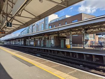 Train at railroad station in city against sky