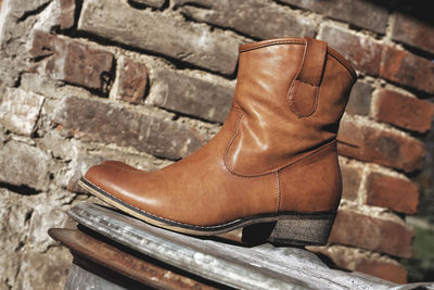 Tilt shot of boots on metal against brick wall