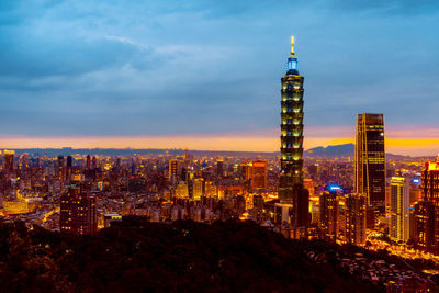 Illuminated buildings in city against sky at night