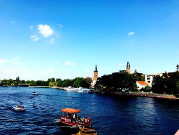 Boats sailing in river against sky in city