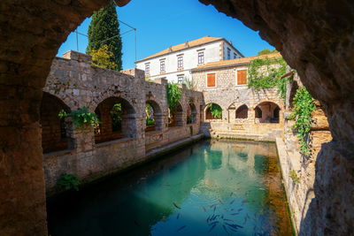 Arch bridge over river against buildings