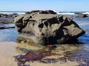 Rock formation on beach against sky