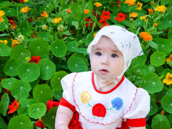Close-up of cute baby girl looking away while standing by plants