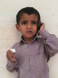 Close-up portrait of boy standing against the wall
