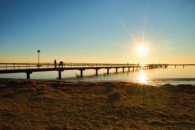 Morning in harbor. tourists walk on pier construction above sea. sunny blue sky, smooth water level