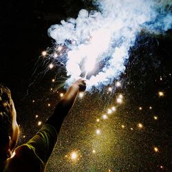 Close-up of hand holding firework display at night