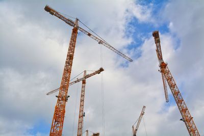 Low angle view of cranes at construction site against sky