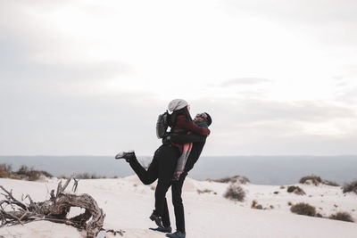 Couple enjoying on snowy land against sky