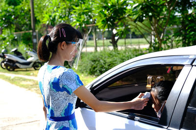 Side view of woman looking through car