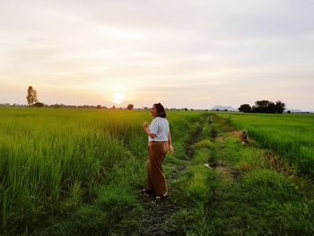 Rear view of woman standing on field against sky