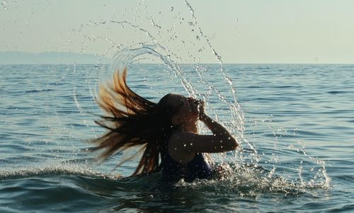 Water splashing in sea against sky