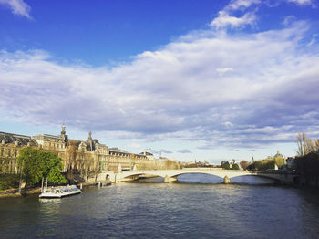 Bridge over river against cloudy sky