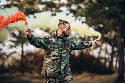 Man holding umbrella standing by tree