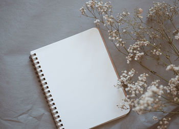 Close-up of blank book with flowers on table
