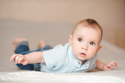 Portrait of cute baby boy sitting on bed at home