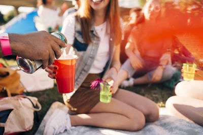 Cropped image of man pouring alcohol in friend's glass at party in festival