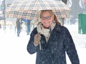 Portrait of smiling young woman standing in city during winter