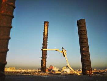 Matchsticks craft by rebars on wall against clear blue sky