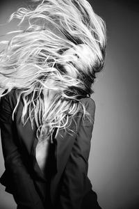 Woman tossing hair against gray background