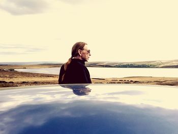 Man standing by car at reservoir shore