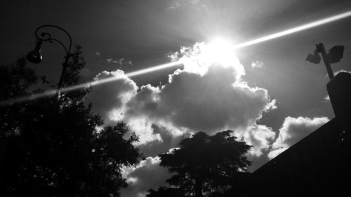 Low angle view of trees against cloudy sky