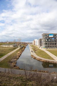 Canal amidst buildings in city against sky