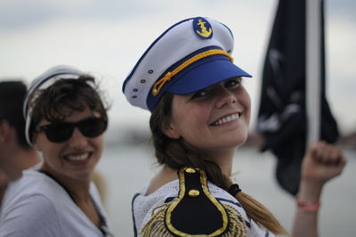 Portrait of smiling mid adult women wearing caps while standing against sky