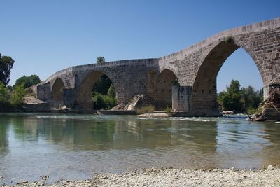 Arch bridge over river against clear sky