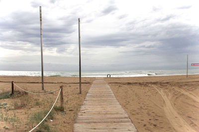 Boardwalk leading towards beach against sky