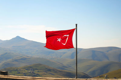 Red flag against mountain range against sky