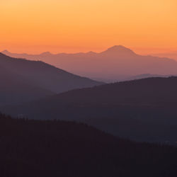 Scenic view of silhouette mountains against orange sky