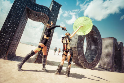 Low angle view of people walking on street against sky