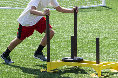 Low section of man playing soccer ball on grass