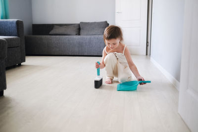 Child with scoop and brush sweeping floor helps to clean house toddlers, development of montessori