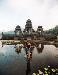 Woman standing in pond against temple