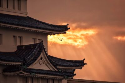 Low angle view of traditional building against sky during sunset