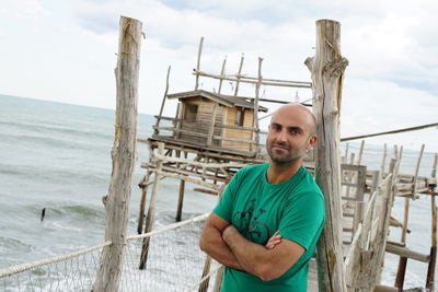 Portrait of bald man standing on pier over sea