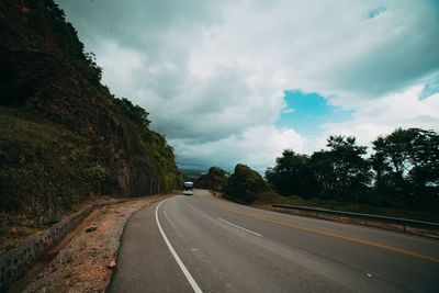Road amidst trees against sky