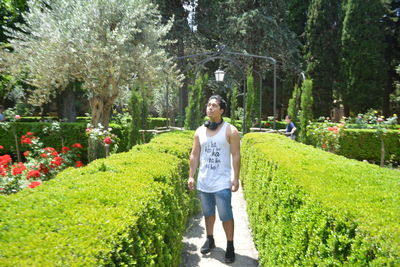 Full length portrait of man standing on flowering plants