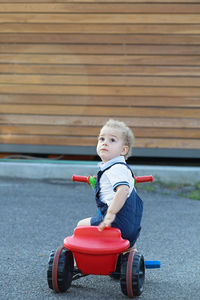 Cute boy looking up while sitting on tricycle
