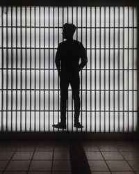 Silhouette man levitating against illuminated window at night