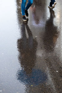 Low section of person with reflection on puddle