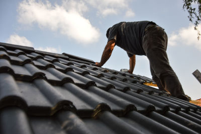 Low section of person standing on roof against sky