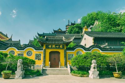 Statue amidst trees and buildings against sky