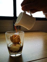 Close-up of hand pouring coffee in cup on table