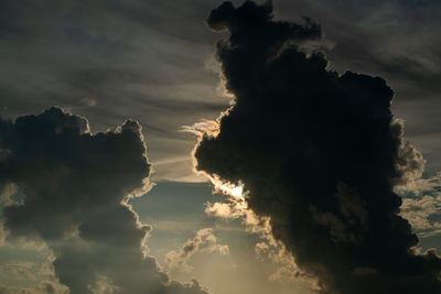 Low angle view of sunlight streaming through clouds