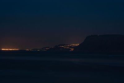 Scenic view of illuminated sea against clear sky at night