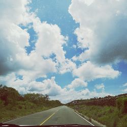 Empty country road against cloudy sky