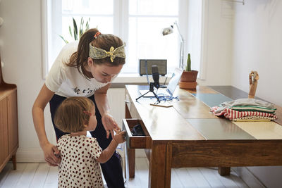 Podcaster looking at daughter opening drawer while standing by table