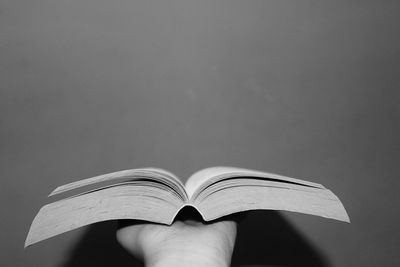 Close-up of hand holding book against gray background